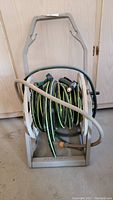 Photo showing the full assembled garden hose on the hose caddie with two nozzles visible at the top of the hose coil.