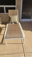 Top down front view of outdoor chaise lounge with brown mesh seating and striped pillow.