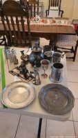 Full view of lot on table including plates, mugs, figurines, teapot and candle holders