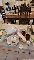Table setup showing various stoneware ramekins, serving bowls, egg cups, and kitchen tools.