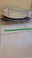 Stack of various serving trays mostly plastic, metal and glass in a pile on floor