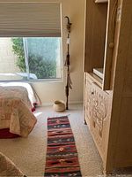 Room view showing spear standing upright near wall, basket on floor and table runner laid on carpet.