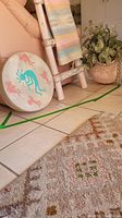 View of drum, ladder with woven pastel blanket, and pot with faux plant near tiled floor and rug