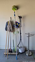 Full view of the cleaning tools, steamer, and towel holder arranged against a wall.