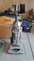 Full view of upright vacuum cleaner with hose attached, showing overall design and condition.
