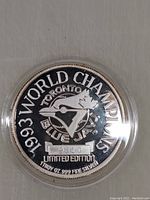 Close-up front side of 1993 Toronto Blue Jays commemorative silver coin in plastic holder showing '1993 World Champions' text and team logo with limited edition serial number.