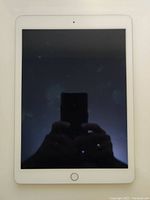 Front view of the silver Apple iPad Air 2 tablet with black screen and home button below display.