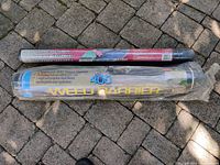 Two rolls of landscape fabric weed barrier lying side by side on a brick surface. One roll is sealed; the other is partially used but mostly intact.