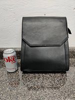 Front view of the Pelle black leather backpack next to a Diet Coke can for size reference.