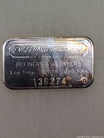 Silver bar with manufacturer details, weight, purity, and serial number visible.