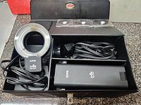 Open case showing Sunpak GX8R ring light, power pack, cables, filters arranged inside.