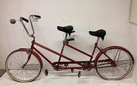 Side profile of red tandem bicycle showing full frame and dual seats