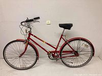 Full side view of the red Columbia women's bicycle showing complete bike, frame design, saddle, fenders, tires, pedals, and handlebars with brake levers and cables.