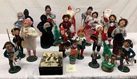 Wide shot showing entire group of 14 caroler figurines and one rectangular music box with illustrated lid.