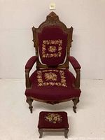Full view of antique Eastlake Victorian wooden armchair with maroon floral needlepoint upholstery and the matching footstool.
