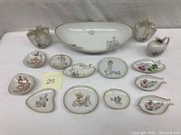 Full group of 15 porcelain items on white background including small dishes and vases with painted designs.