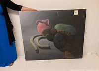 Full view of the large oil painting held by a person showing stylized human organs as subject.