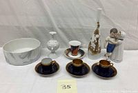 Full lot displayed: 3 decorative Rosenthal espresso cups and saucers, Royal Copenhagen porcelain figurine couple, two vases of different sizes, and a white decorated bowl.