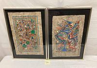 Pair of framed Mexican folk art paintings on amate bark paper showing birds and village scenes, side by side for lot overview