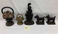 Five cast iron doorstops: two flower baskets, one ornate scroll, two Scottie dogs, all vintage