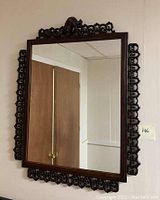 Full view of the large rectangular mirror with visible wooden frame and lattice decoration.