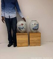 Full view of both vases on wooden cubes with person for scale