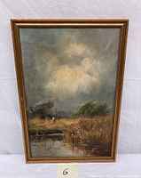 Full view of vintage oil painting showing wetland landscape with water, grasses, birds under cloudy sky in a gold detailed frame.