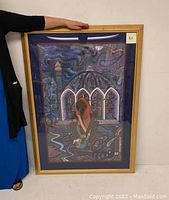 Full view of framed oil painting showing the Islamic themed artwork with figure and dome structure in blue and purple tones.