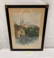 Full view of framed watercolor etching showing landscape scene with water, homes, and church spires.