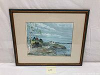 Front view of the framed watercolor painting showing coastal landscape with houses and trees.