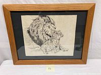 Framed pen and ink drawing depicting a lion and its cub with a wood frame and black mat.
