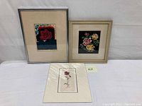 Three framed floral artworks displayed together showing different styles and flowers.