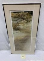 Full view of the framed watercolor painting showing sand dunes and rocky landscape with vegetation, matted and framed under glass.
