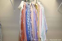 Photo of 16 men's dress shirts hanging on a rack showing a variety of colors and patterns including stripes and checks.