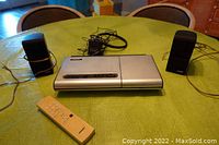 BOSE Lifestyle Model 5 set on table showing CD player, two mini speakers, wires, power adapter, and beige remote control.