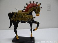 Full view of the tin metal horse sculpture showing the entire figure mounted on a black rectangular base with a raised right foreleg.