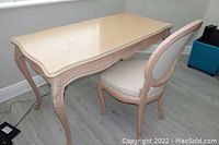 Overall view of the blonde wood French Provincial writing desk with blue painted highlights on the carved legs and tabletop trim, showing the shape and condition of the desk.