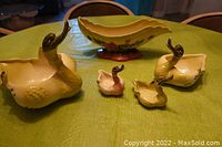 Five-item set of vintage Hull Pottery including three goose figure containers and one floral scalloped bowl on a green table.