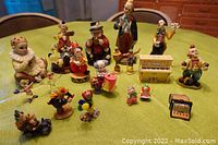 Lot displayed on green tablecloth showing all 19 clown figurines in varying poses and sizes.