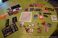 Overview of collection laid out on green fabric showing patches, buttons, pins, small cards, and badges representing multiple rock bands