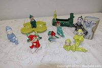 Wide view of the lot showing all ten elf pixie ceramic pieces arranged on a tablecloth, including planters and various figurines in bright colors