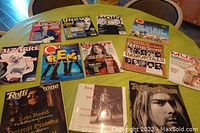 Photo showing entire lot of 12 music magazines and books laid out on a table with covers visible including Rolling Stone, Q, Uncut, Mojo, Bizarre, Muzic and a punk book.