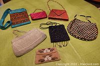 Seven vintage ladies evening bags on green fabric background, showing variety of beadwork, mesh, fabric styles and chains.