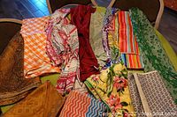 Lot displayed on chairs and table showing variety of tablecloths and runners with multiple colors and patterns.