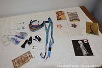 Full lot items arranged on table including bracelets, lanyards, key, chargers, cords, banknote, and greeting cards.