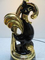 Side view of the black and gold pottery rooster lamp showing detail on the tail and comb