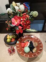 Wood bowl with assorted Murano glass fruit alongside black wire bowl with faux fruit and small red glass flower bowl.
