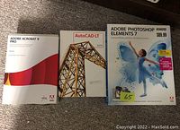 Photo showing three boxed software titles: Adobe Acrobat 9 Pro, AutoCAD LT 2009, Adobe Photoshop Elements 7.