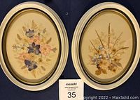 Two oval framed dried flower arrangements on a dark blue background, showing full frames and floral detail.