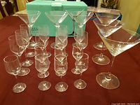 Set of 16 clear Rosenthal Studio Line goblets and 6 Rosenthal diVino Martini glasses arranged on table with turquoise box in background